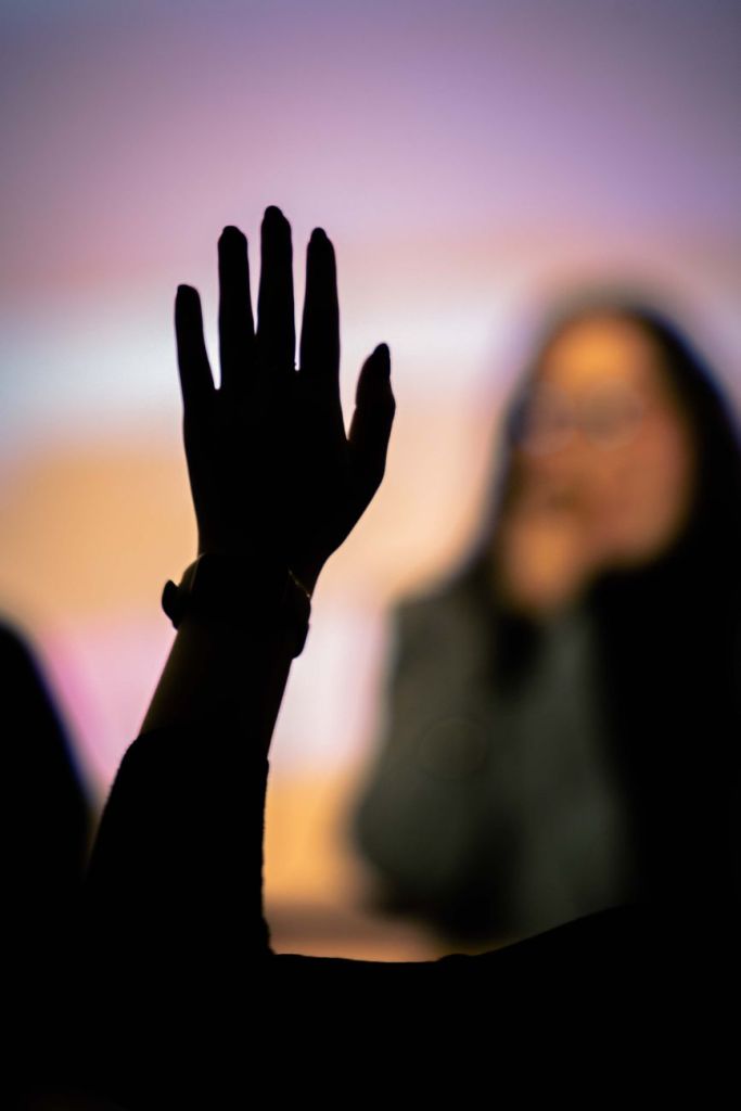 silhouette of raised hand in audience setting