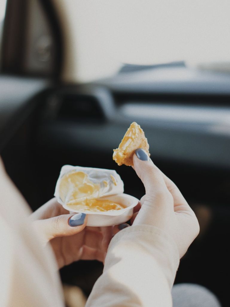 hands of a person holding food and a dip